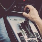 Detail of a hand pulling an automatic gear shifter in a new car.